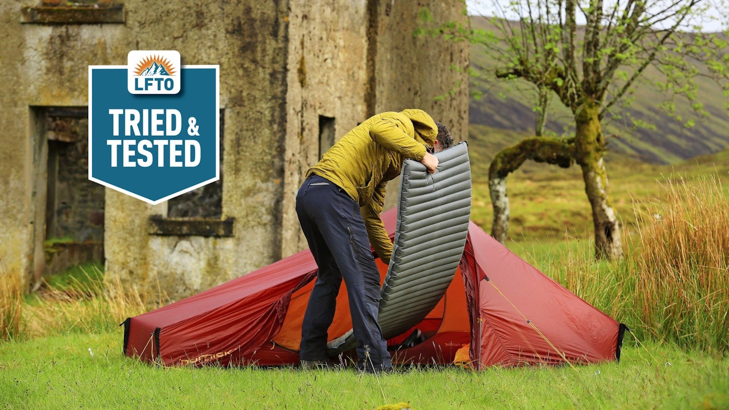 Putting sleeping mat inside tent, wild camp by ruined haunted house bothy, West Highlands Scotland