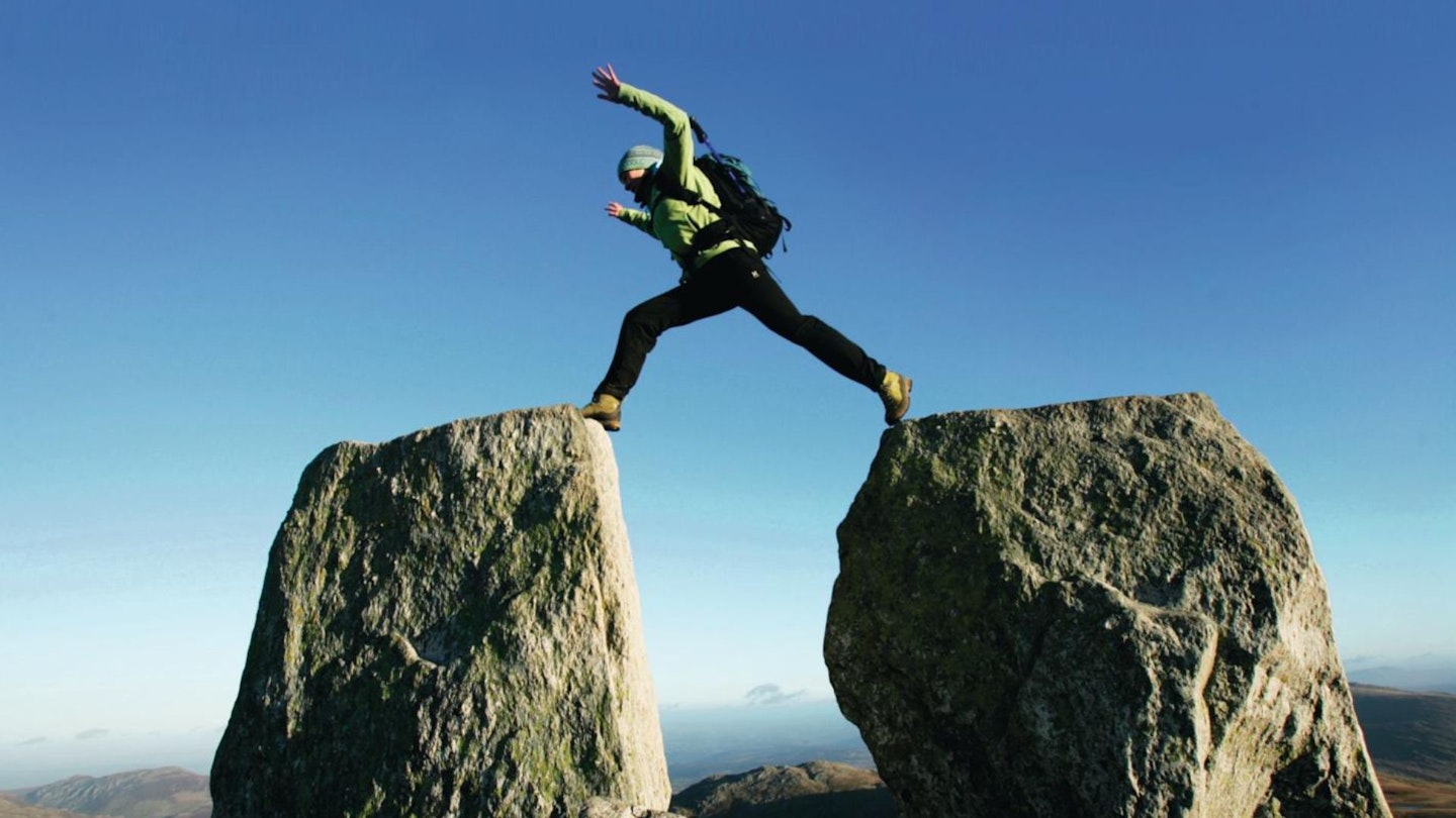 Hiker jumping Adam and Eve, Tryfan, Snowdonia