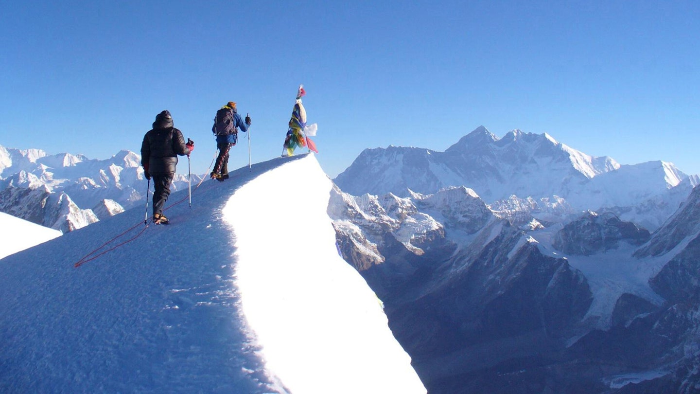 Team members of the British Army expedition approaching the 6476m summit of Mera Peak, with early morning light illuminating Mount Everest in the background