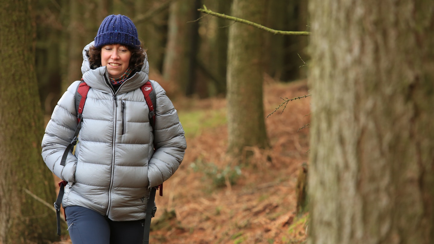 Hiker walking in the woods wearing a grey down jacket